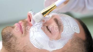 美容师正在用刷子`人脸上涂白色<strong>保湿面膜</strong>。